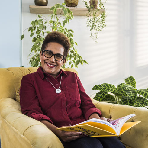 woman smiling an reading a book on a chair